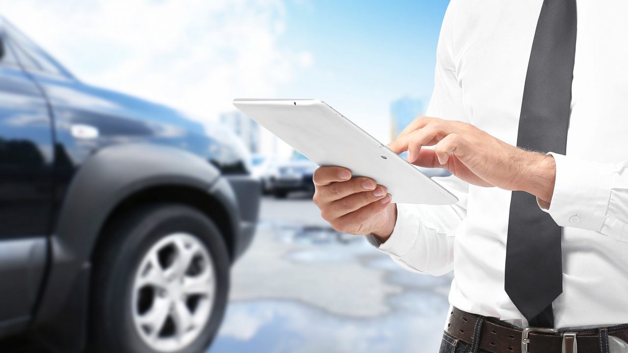 Insurance agent using tablet and car on background